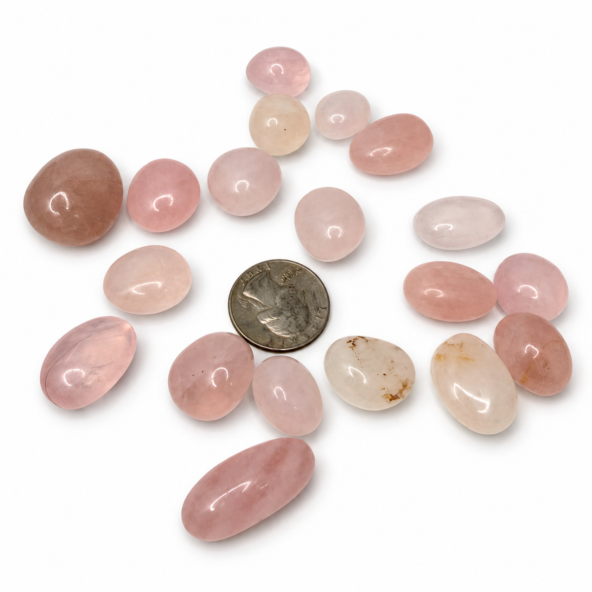 Polished rose quartz tumbled stones in shades of pink, next to a quarter for scale - Magick Souls