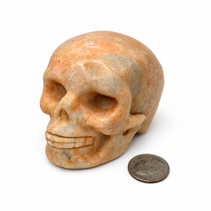 Hand carved peach calcite skull showing carved eye sockets and teeth - Magick Souls