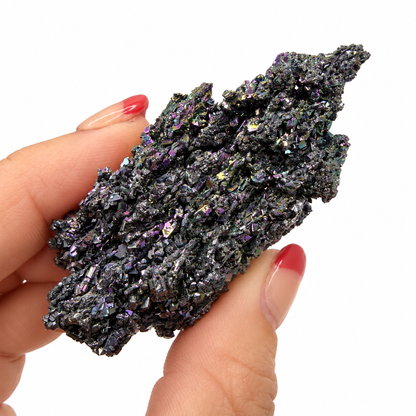 Raw Carborundum crystal specimen with purple and green iridescent sparkle held in fingers