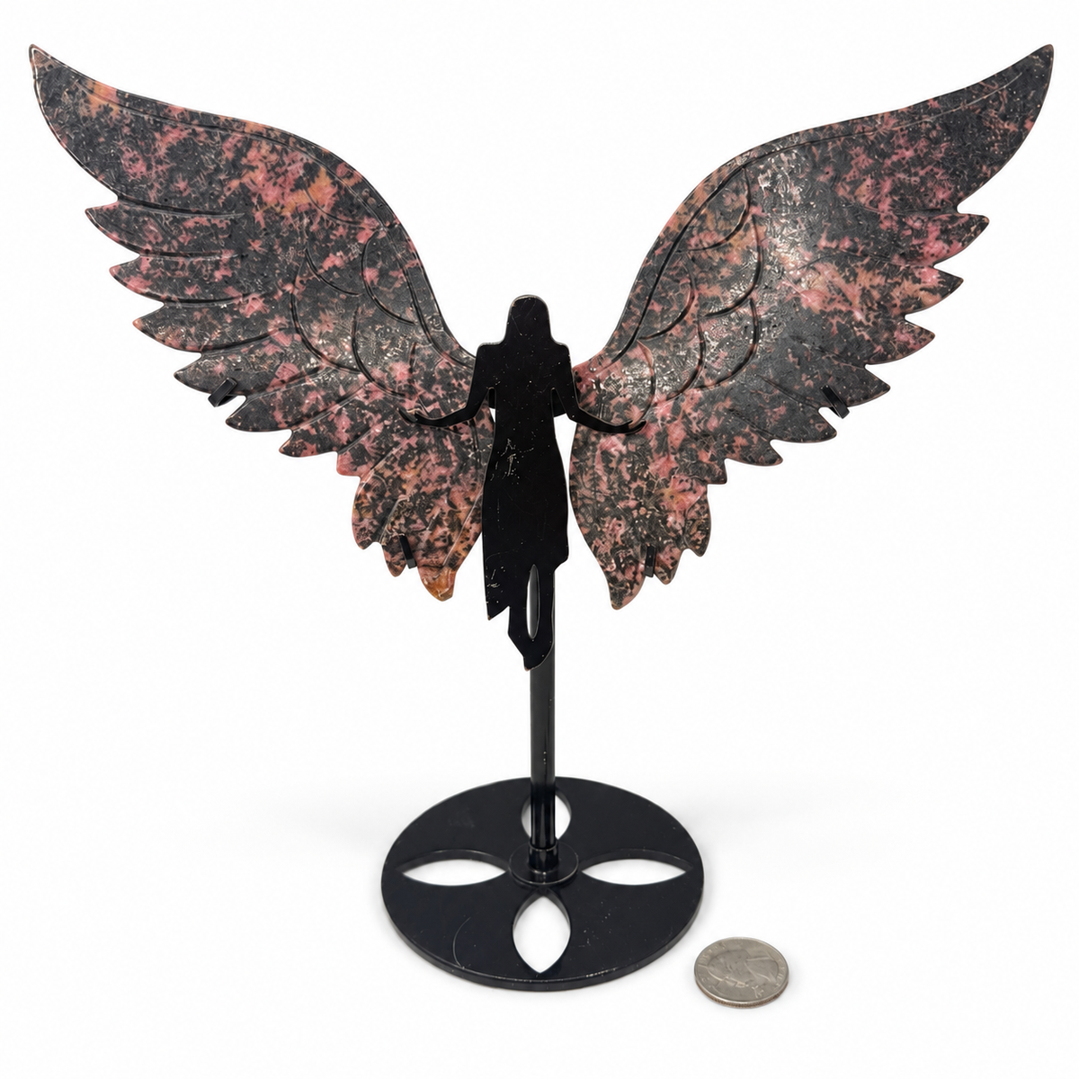 Rhodonite winged goddess, carved pink and black crystal angel wings on black metal goddess stand, next to a quarter for scale - Magick Souls